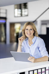 Businesswoman holding tablet PC at workplace - PESF03348