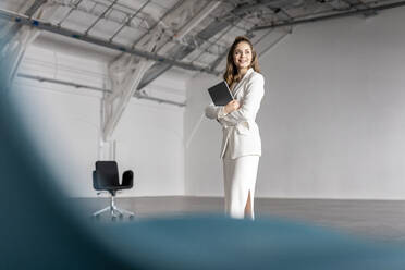 Nachdenkliche Geschäftsfrau mit Tablet-PC in einer Industriehalle - PESF03405