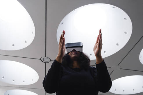 Frau gestikuliert in einem Virtual-Reality-Simulator - ASGF01963