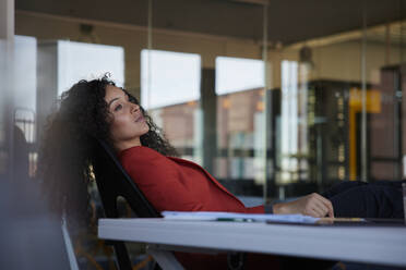 Businesswoman day dreaming while sitting on chair at workplace - RBF08477