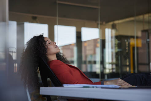 Geschäftsfrau ruht mit geschlossenen Augen auf einem Stuhl im Büro - RBF08478