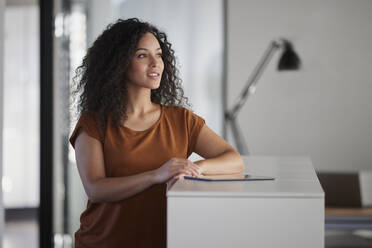 Businesswoman with tablet PC day dreaming in office - RBF08506