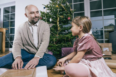 Vater und Tochter verpacken zu Hause sitzend ein Weihnachtsgeschenk - KMKF01782