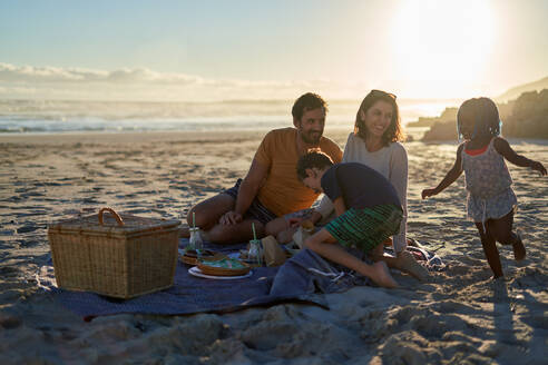 Glückliche Familie bei einem Picknick am sonnigen Sommerstrand - CAIF31988
