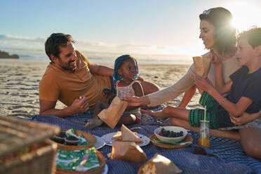 Glückliche Familie bei einem Picknick am sonnigen Sommerstrand - CAIF31990