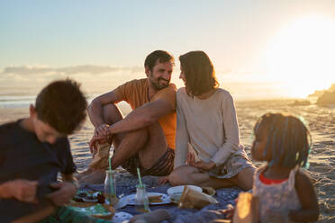 Glückliches Paar beim Picknick mit Kindern am sonnigen Sommerstrand - CAIF32020