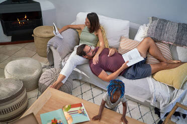 Familie entspannt und liest auf dem Wohnzimmersofa - CAIF32021