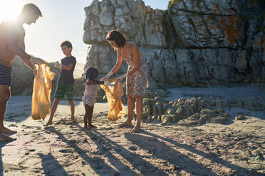 Family volunteering picking up garbage on sunny beach - CAIF32031