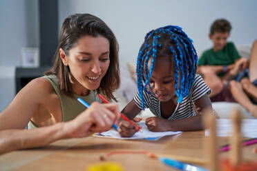 Mother and toddler daughter coloring at home - CAIF32033