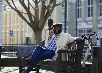 Geschäftsmann spricht auf einer Bank im Stadtpark mit seinem Smartphone - CAIF32038