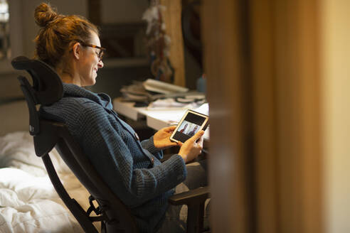 Frau, die von zu Hause aus per Videochat mit Kollegen auf einem digitalen Tablet arbeitet - CAIF32046