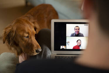 Man with dog video chatting at laptop screen - CAIF32102