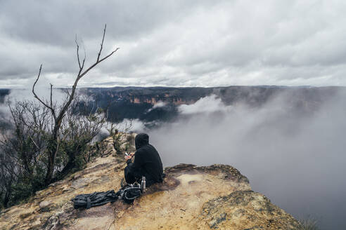 Männlicher Wanderer rastet auf einer abgelegenen Bergkuppe, Australien - CAIF32112