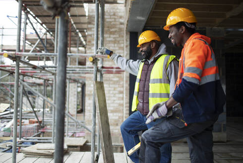 Männliche Bauarbeiter unterhalten sich auf der Baustelle - CAIF32116