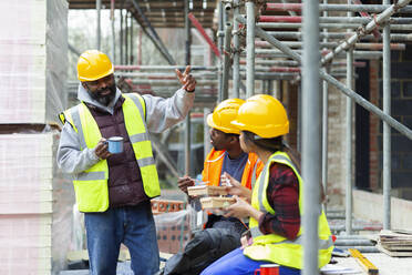 Construction workers enjoying lunch break at construction site - CAIF32118