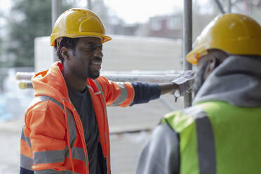 Männliche Bauarbeiter unterhalten sich auf der Baustelle - CAIF32120