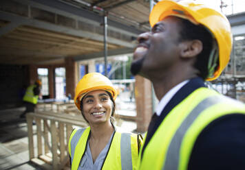 Happy construction workers talking at construction site - CAIF32122