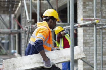 Bauarbeiter trägt Holz auf einer Baustelle - CAIF32125