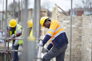 Construction worker assembling scaffolding at construction site - CAIF32128