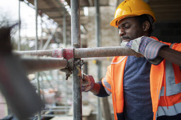 Male construction worker assembling scaffolding at construction site - CAIF32129