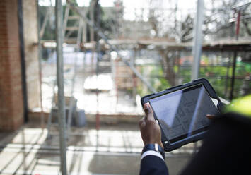Ingenieur sieht sich auf der Baustelle Pläne auf einem digitalen Tablet an - CAIF32131