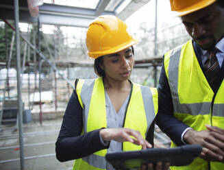 Architects with digital tablet at construction site - CAIF32150