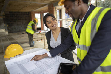 Architect and engineer reviewing blueprints at construction site - CAIF32151