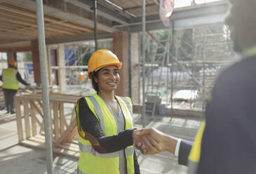 Architect and forewoman shaking hands at construction site - CAIF32153