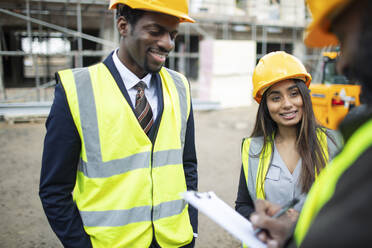 Architects and foreman talking at construction site - CAIF32155