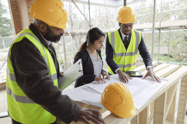 Architekten und Ingenieure beim Betrachten von Bauplänen auf der Baustelle - CAIF32158