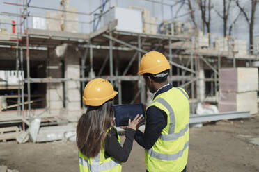 Engineers with digital tablet at sunny construction site - CAIF32174