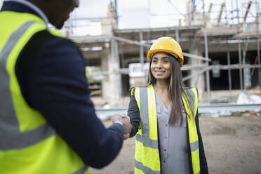 Engineer and forewoman shaking hands at construction site - CAIF32180