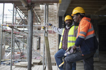Männliche Bauarbeiter unterhalten sich auf der Baustelle - CAIF32187