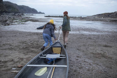 Junges Paar, das ein Kanu am Strand zieht, Kent, UK - CAIF32198