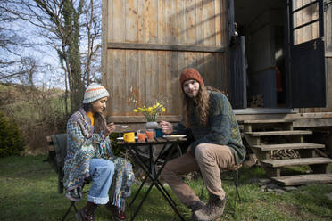 Porträt junges Paar essen am Tisch außerhalb winzige Hütte mieten - CAIF32221