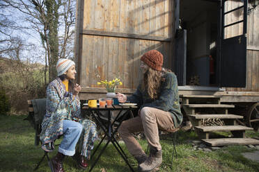 Glückliches junges Paar beim Essen vor einer kleinen gemieteten Hütte - CAIF32226