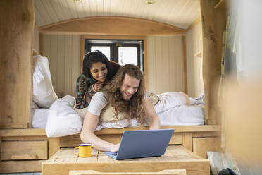 Glückliches junges Paar benutzt Laptop in kleinem Kabinenbett - CAIF32227