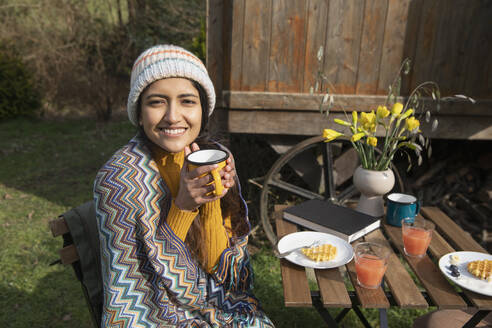 Portrait happy young woman enjoying breakfast at campsite - CAIF32229