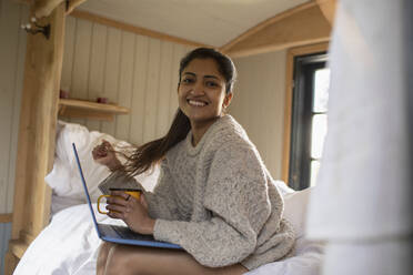 Portrait happy young woman using laptop in bed - CAIF32242