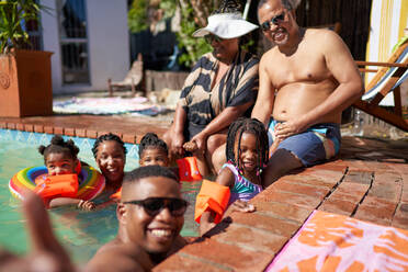 Portrait happy multigenerational family at sunny summer swimming pool - CAIF32258