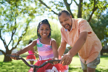 Porträt glücklicher Großvater und Enkelin beim Fahrradfahren im Park - CAIF32259