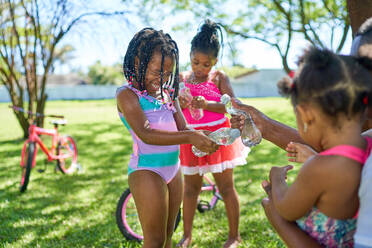 Verspielte Mädchen spritzen Wasser im Sommerpark - CAIF32262
