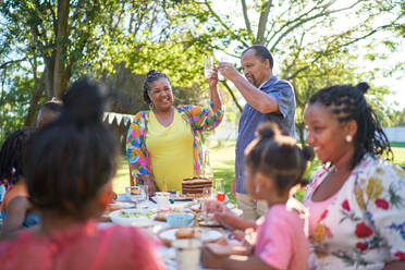 Glückliche Mehrgenerationen-Familie feiert Geburtstag im sommerlichen Hinterhof - CAIF32278