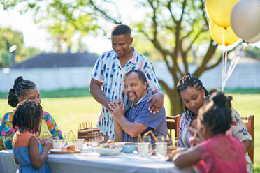 Multigenerational family celebrating birthday at summer patio table - CAIF32282