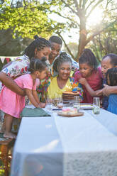 Multigenerational family celebrating birthday with cake at patio table - CAIF32287