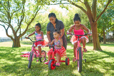 Mutter und Töchter mit Fahrrädern und Dreirädern im Sommerpark - CAIF32289
