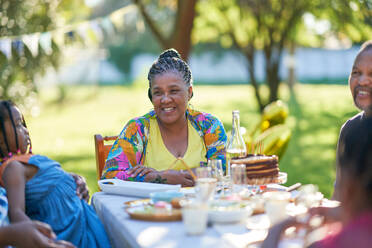 Happy woman celebrating birthday with family at patio table - CAIF32301