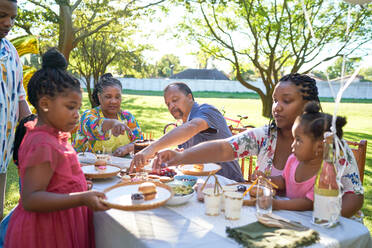 Multigenerational family celebrating birthday at summer patio table - CAIF32307