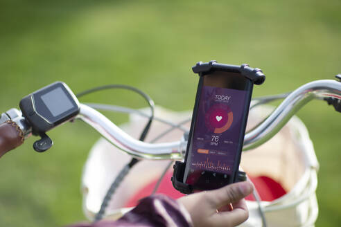 POV woman on bicycle checking heart rate with smart phone app - CAIF32326