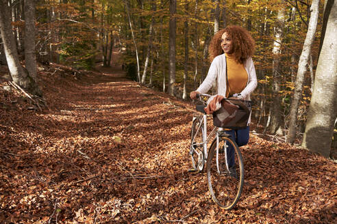Frau mit Fahrrad auf Wanderweg im Herbstwald - VEGF05265